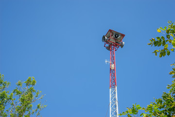 Speaker on high tower and clear sky with tree as a foreground
