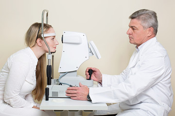 Young woman having her eyes examined by an eye handsome elderly