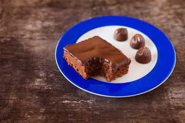 Piece of chocolate cake on a plate on wooden table background