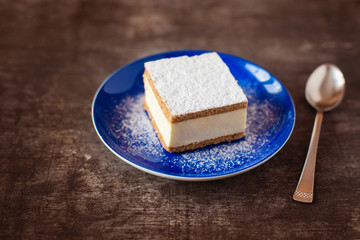 Piece of cake on a plate on wooden table background.