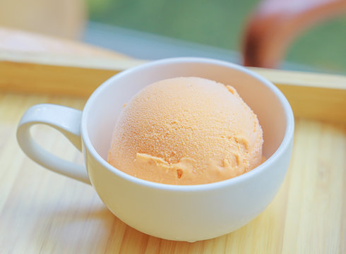 Ice cream in the cup on the wooden board