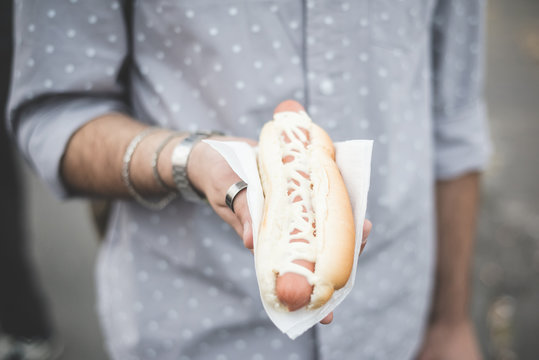 close up of young man hand holding hot dog