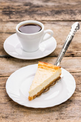 Slice of cheesecake on plate with cup of coffee