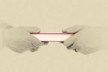 Closeup of mature man´s hand giving a book to his son,conceptua