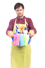 Unhappy young man with apron and cleaning equipment