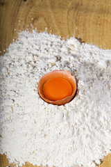 Closeup of broken egg on flour