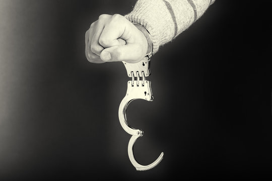 Closeup of unlocked handcuffs hanging on man hand