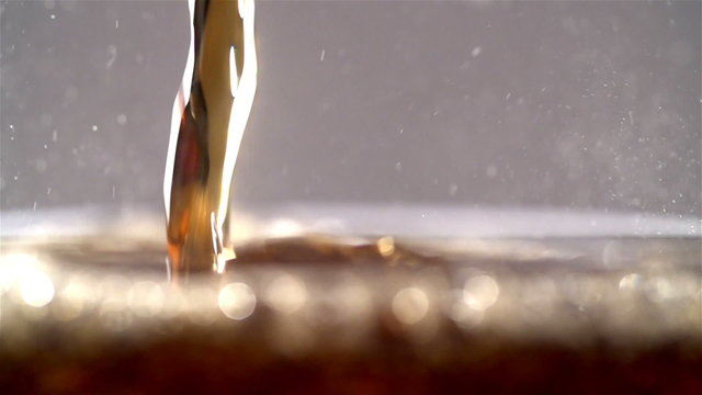 Cola carbonated drink pouring in glass with splash. Slow motion