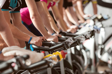 gym detail shot - people cycling, spinning class - obrazy, fototapety, plakaty