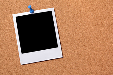 One single polaroid style photo frame print pinned to a cork notice board background 