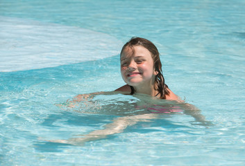 Joyful smiling little girl enjoying her leisure time in pool