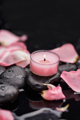 Red rose petals with candle and therapy stones 