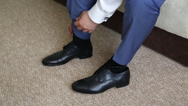 Man is tying his black shoes
