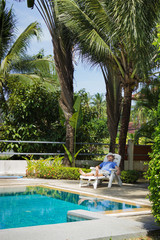 Obraz premium Elderly tourist resting by the pool