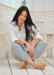 Beautiful smiling  young woman relaxing in hammock at home