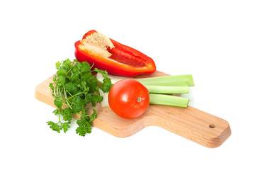 Vegetables (pepper, tomato, parsley) lie on cutting board