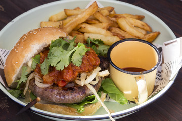 Gourmet sausage hamburger with fries and a cup of ketchup
