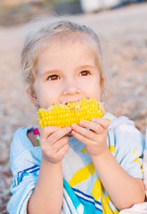 Toddler cute girl eating boiled corn