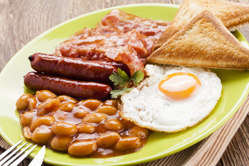 Full english breakfast with bacon, sausage, fried egg, baked bea