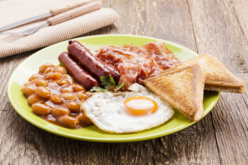 Full english breakfast with bacon, sausage, fried egg, baked bea