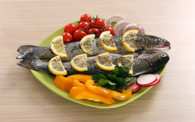prepared trout with lemon and salad on plate