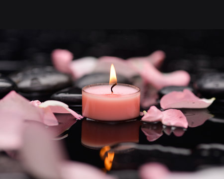 Beautiful rose petals with candle and therapy stones