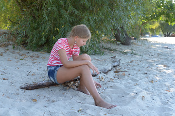 Little girl teenager sitting on the sand