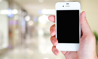 Smart phone in hand on blur store with bokeh background