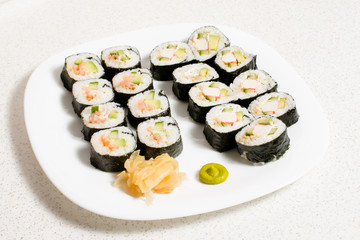 Homemade sushi in a white plate with wasabi and ginger