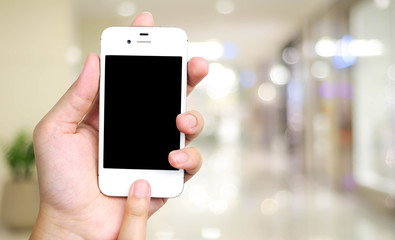 Smart phone in hand on blur store with bokeh background