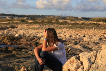 Thinking young (25-30) Sicilian girl near the beach at sunset.  