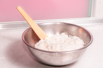 Fototapeta na wymiar Cooked white rice in a metal bowl and wooden spoon stirrer