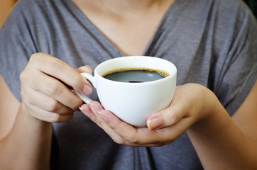 a young female holding a cup of coffee for drinking