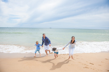 A four people family is playing in the sea waves