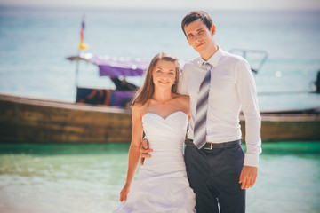 bride and groom embrace standing on sand beach