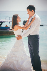 bride and groom embrace standing on sand beach