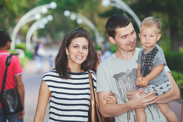 Young family with child walks in summer alley