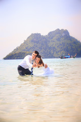 bride and groom embrace half in shallow water