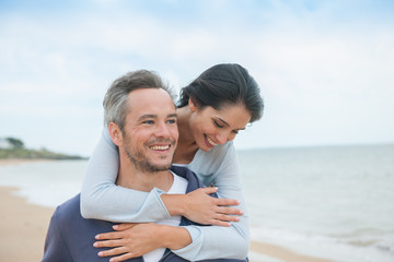 A beautiful couple is posing holding eachother at the beach