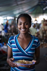 Young woman, eating while working at a street market in Nairobi