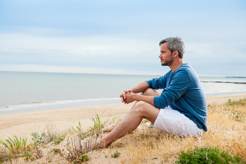 An attractive man is sitting face to the ocean