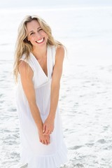 Fototapeta na wymiar Smiling blonde in white dress looking at camera