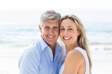 Fototapeta premium Happy couple standing by the sea and smiling at camera