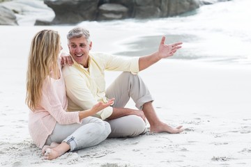 Fototapeta premium Happy couple sitting on the sand