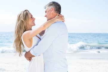 Obraz premium Happy couple smiling at each other by the sea