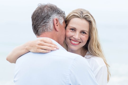 Happy couple hugging each other by the sea