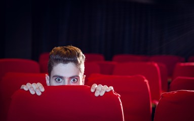 Young man watching a scary film - Powered by Adobe