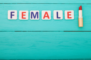 Word female and red lipstick on blue wooden background