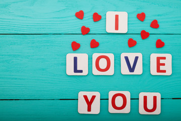 Words I love you with hearts on wooden background