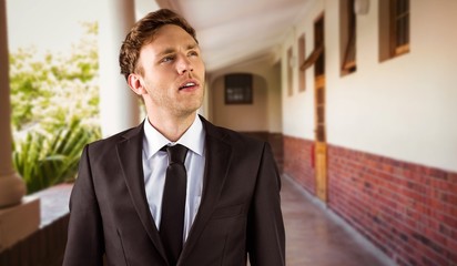 Composite image of young businessman thinking and looking up